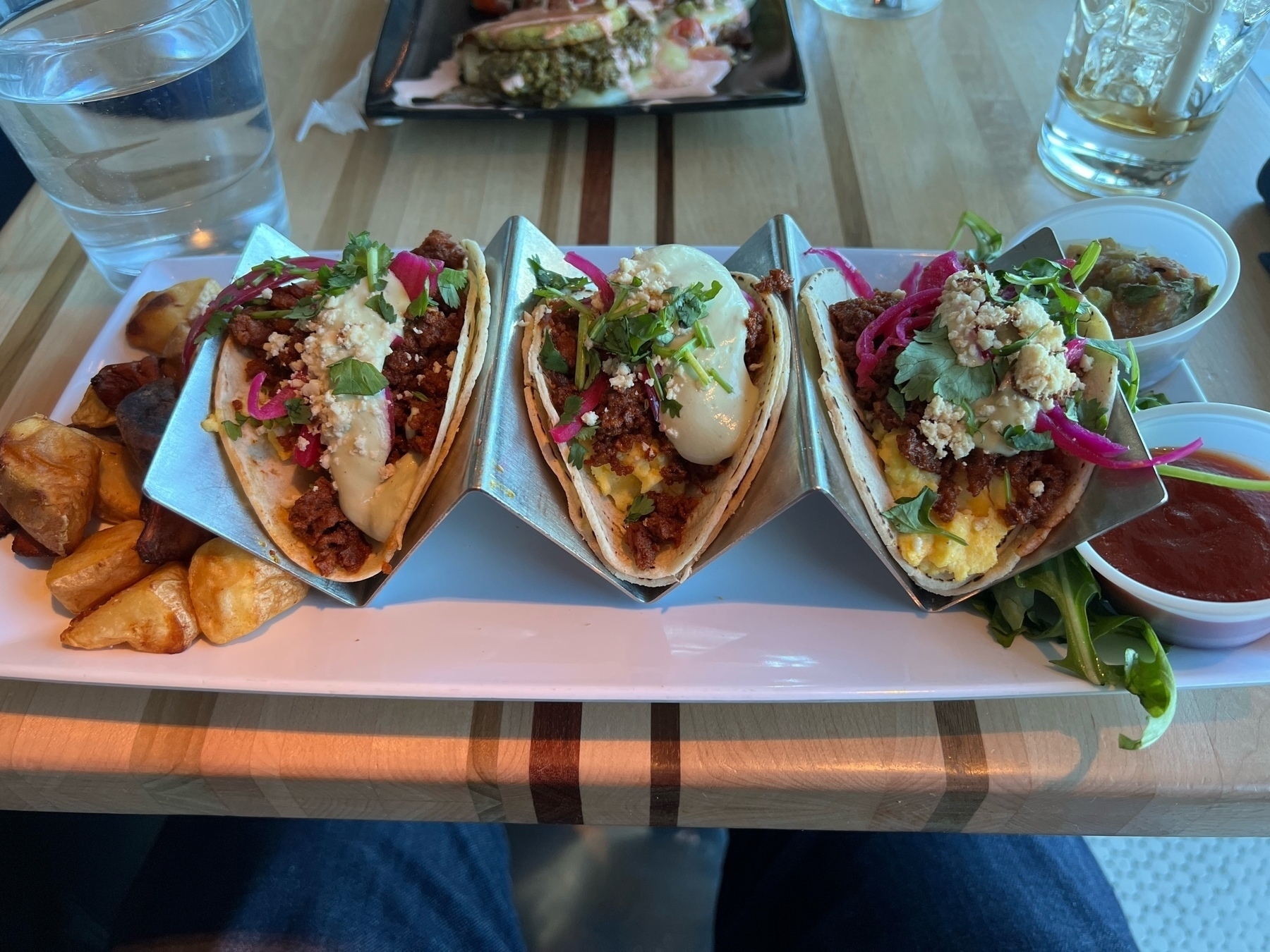 Three breakfast tacos on a wood table.