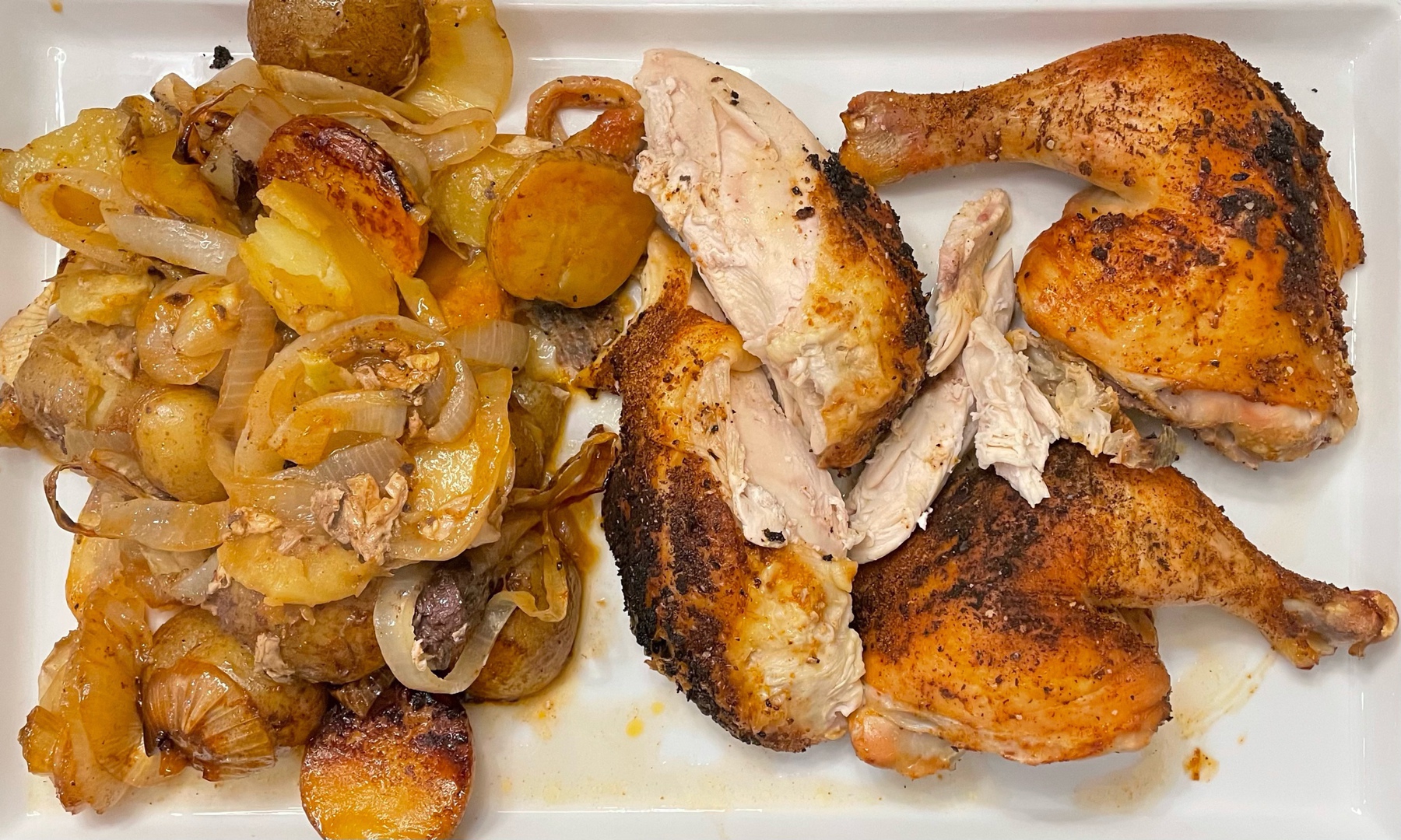 Whole chicken cooked and butchered into parts alongside potatoes and onions