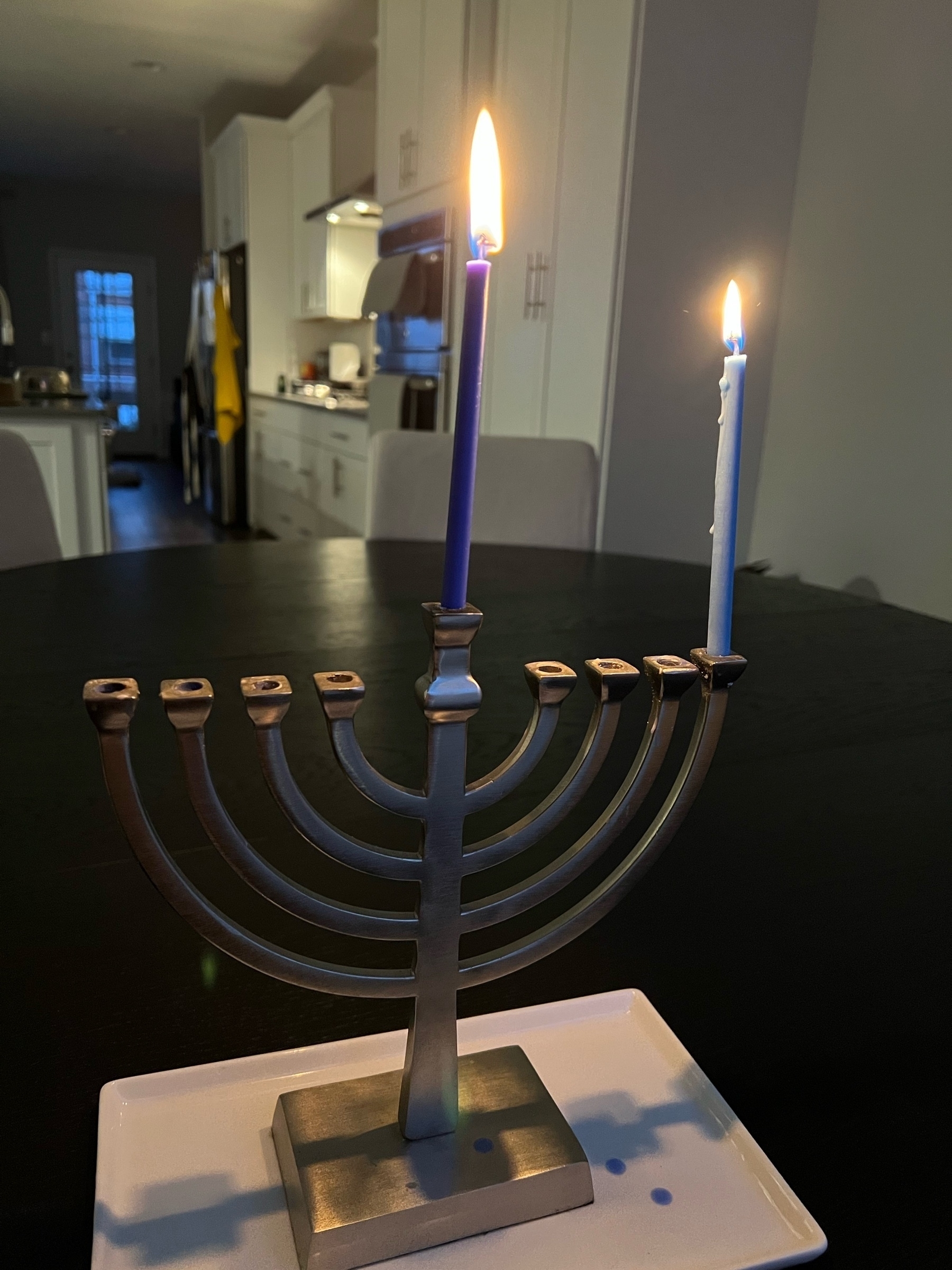 First night of Hanukkah, silver menorah with lit candles.