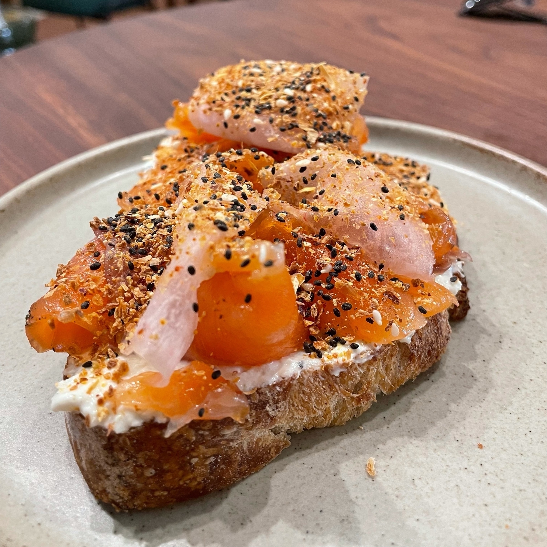 Lox and radish on labneh and sourdough, with a sprinkle of various seeds on top.