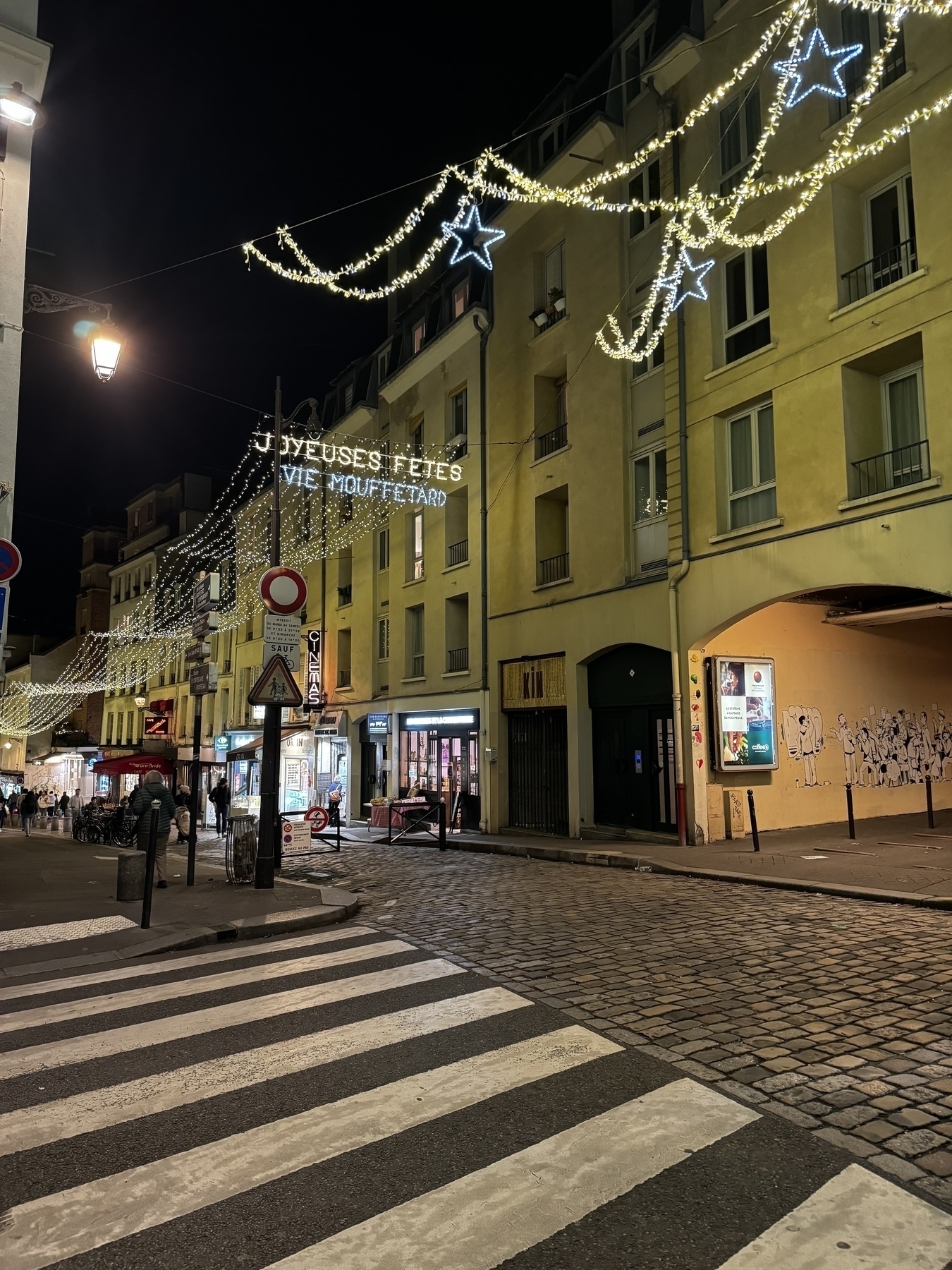 Parisian street corner with string lights hung above between the buildings.
