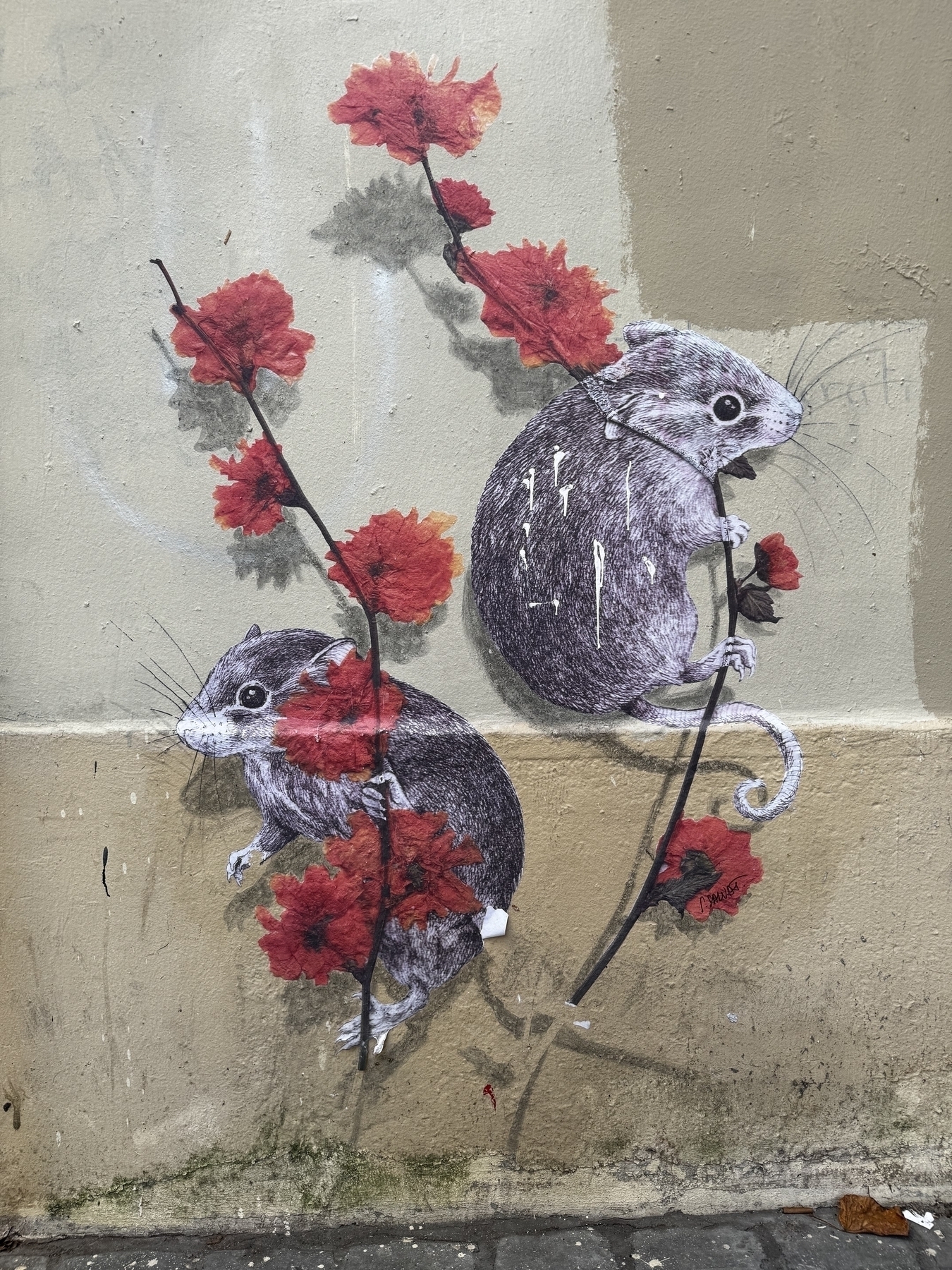 Exterior beige wall painted with two small mice clutching the stems of red flowers.